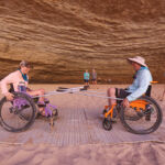 Two people in wheelchairs laughing in a cave